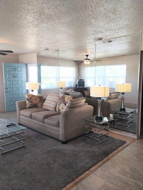 living room featuring ceiling fan, a textured ceiling, and plenty of natural light