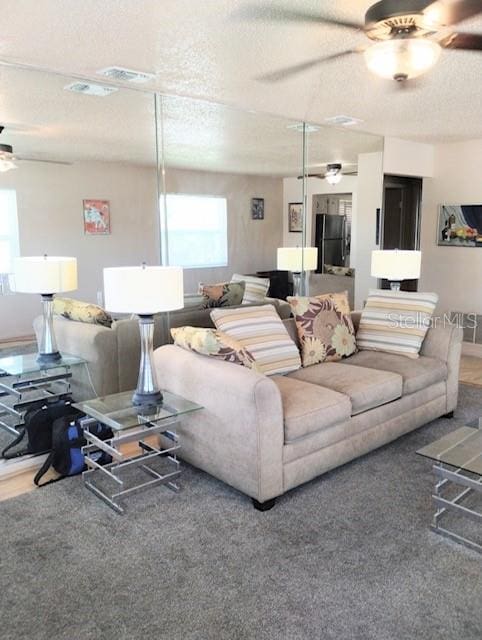 carpeted living room featuring a textured ceiling and ceiling fan