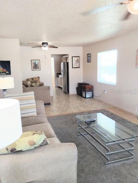 living room featuring ceiling fan and a textured ceiling