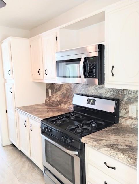 kitchen with white cabinetry, stainless steel appliances, and tasteful backsplash