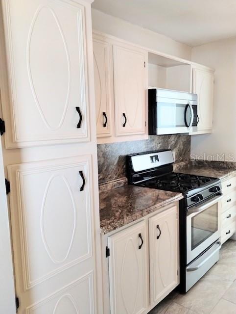 kitchen with decorative backsplash, white cabinetry, stainless steel appliances, and dark stone counters