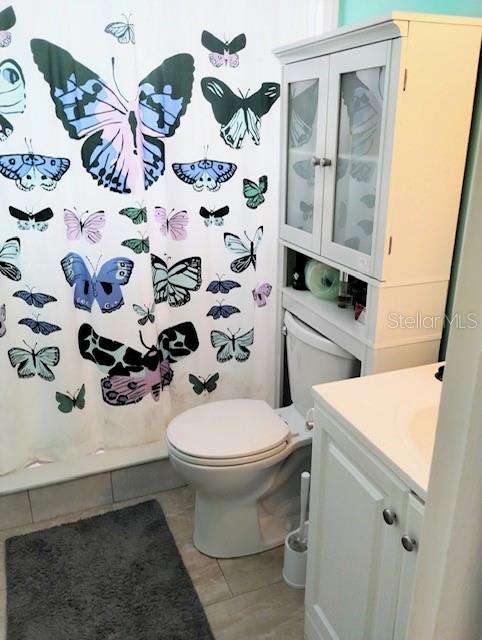 bathroom with vanity, a shower with shower curtain, toilet, and tile patterned flooring