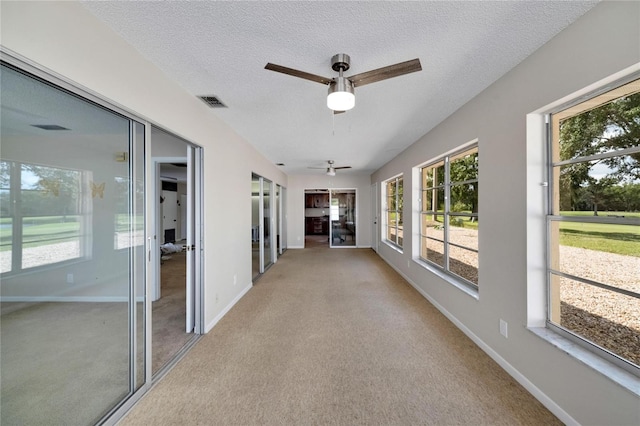 unfurnished sunroom featuring ceiling fan