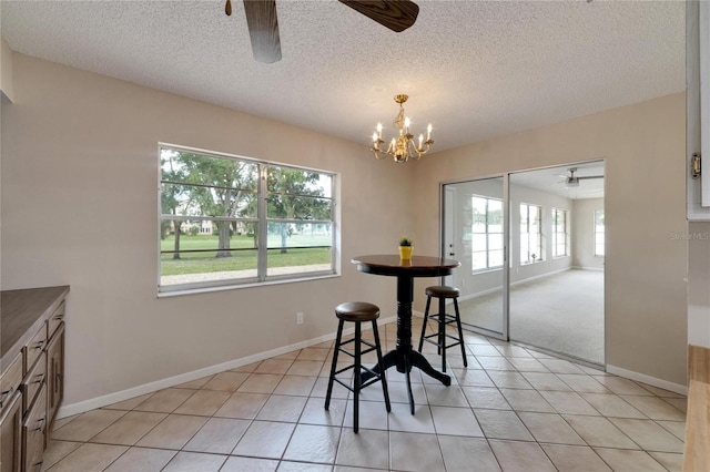 dining area featuring a textured ceiling, ceiling fan with notable chandelier, and light tile patterned flooring