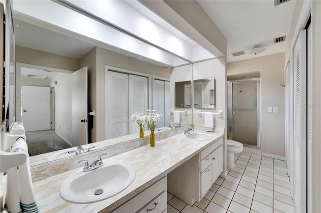 bathroom featuring toilet, vanity, tile patterned floors, and a shower with shower door