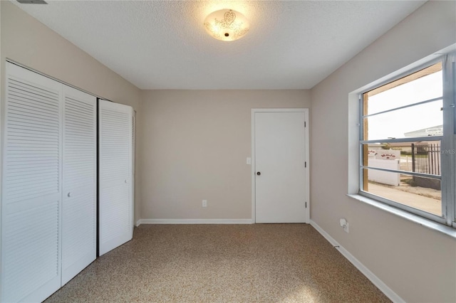 unfurnished bedroom featuring a textured ceiling and a closet