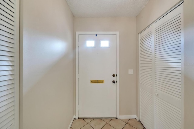 doorway to outside with light tile patterned floors and a textured ceiling