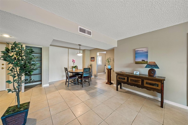 dining space with a textured ceiling and light tile patterned floors