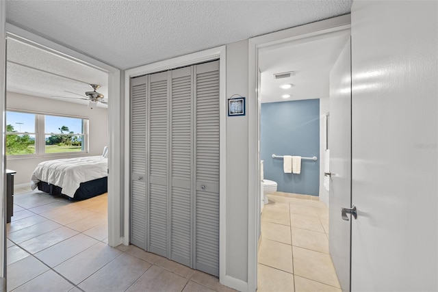 corridor with a textured ceiling and light tile patterned floors