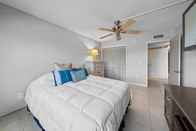 bedroom featuring a textured ceiling, a closet, ceiling fan, and light tile patterned flooring