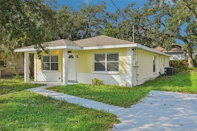 bungalow featuring a front lawn and central AC unit