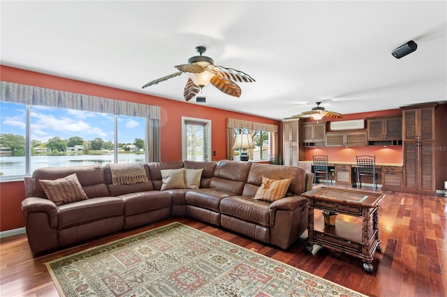 living room featuring a wall mounted air conditioner, dark hardwood / wood-style flooring, plenty of natural light, and ceiling fan