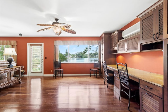 office space featuring built in desk, a healthy amount of sunlight, a wall mounted AC, and dark hardwood / wood-style flooring