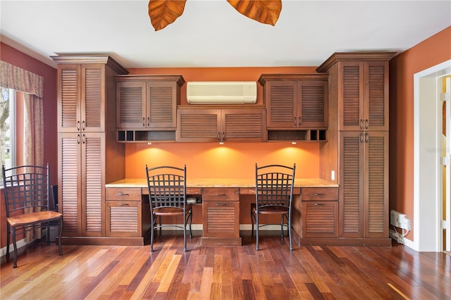 kitchen featuring built in desk, light stone countertops, a wall mounted air conditioner, and dark hardwood / wood-style floors