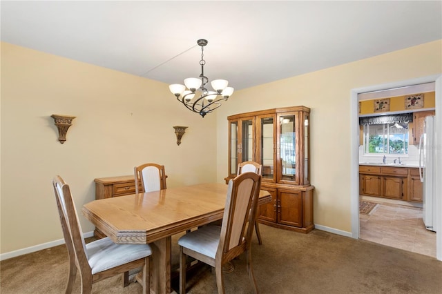 carpeted dining room featuring an inviting chandelier and sink