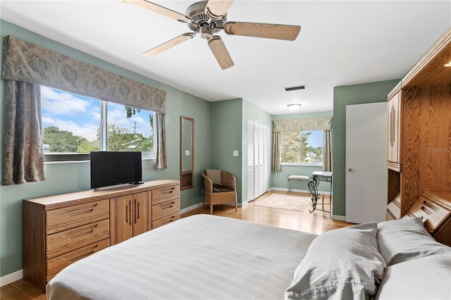 bedroom with a closet, multiple windows, light hardwood / wood-style floors, and ceiling fan