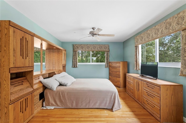 bedroom with ceiling fan, multiple windows, and light wood-type flooring