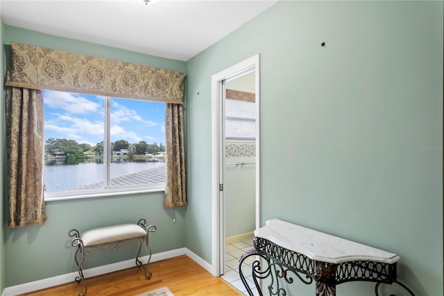 sitting room with hardwood / wood-style floors and a water view