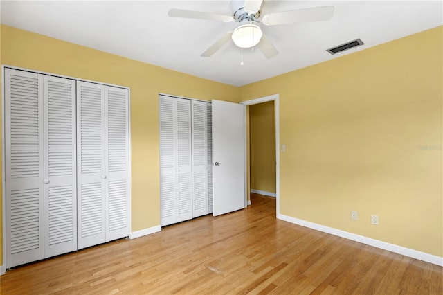 unfurnished bedroom featuring light hardwood / wood-style floors, two closets, and ceiling fan