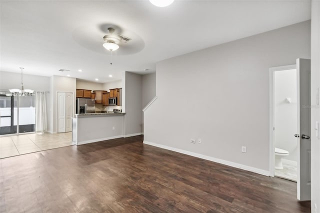 unfurnished living room featuring ceiling fan with notable chandelier and hardwood / wood-style floors