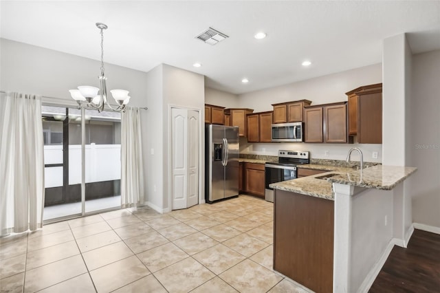 kitchen with appliances with stainless steel finishes, light stone countertops, sink, a notable chandelier, and decorative light fixtures