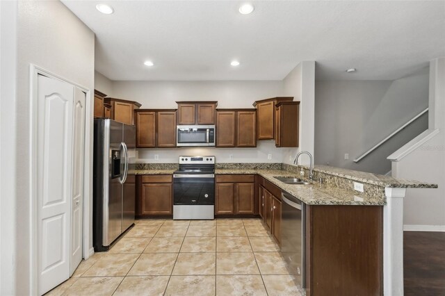 kitchen featuring kitchen peninsula, sink, light stone countertops, light tile patterned floors, and appliances with stainless steel finishes