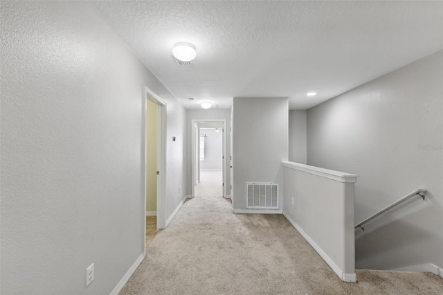 hallway featuring light carpet and a textured ceiling