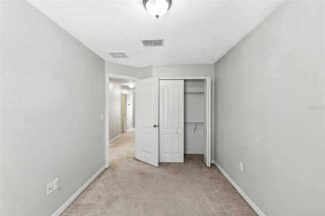 unfurnished bedroom featuring a closet and light colored carpet