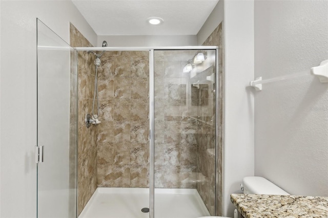 bathroom with toilet, a textured ceiling, vanity, and a shower with door