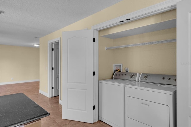 laundry area with washer and dryer, light tile patterned floors, and a textured ceiling