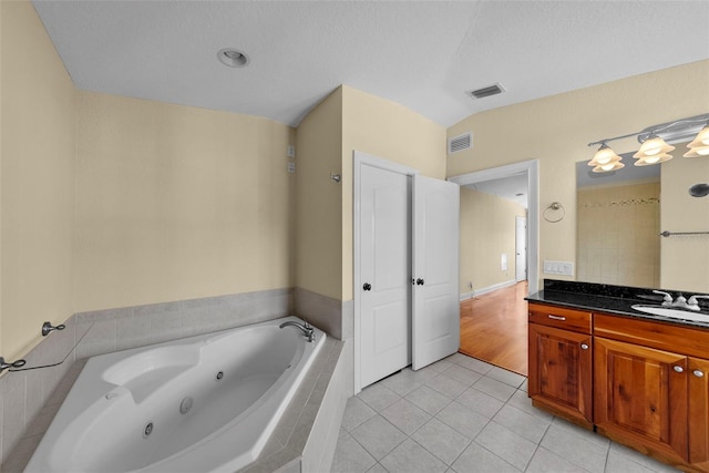 bathroom featuring tiled bath, tile patterned flooring, vanity, and a textured ceiling