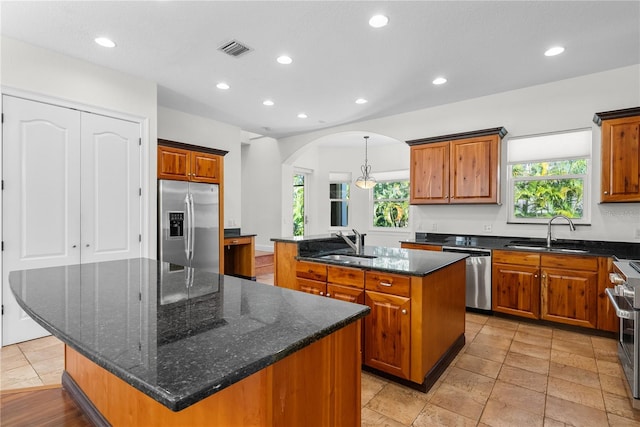 kitchen with a large island with sink, stainless steel appliances, a healthy amount of sunlight, and sink