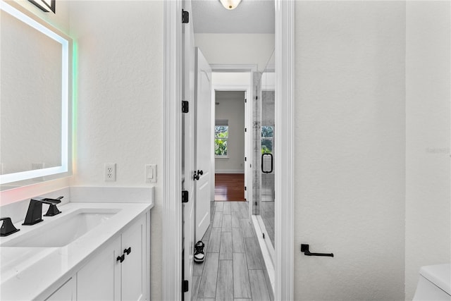 bathroom with vanity, toilet, an enclosed shower, and wood-type flooring