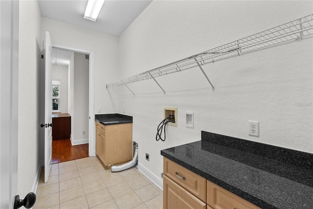 laundry area with cabinets, washer hookup, light tile patterned floors, a textured ceiling, and hookup for an electric dryer