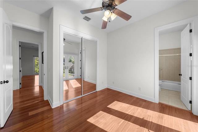 unfurnished bedroom featuring hardwood / wood-style floors, ensuite bath, a closet, and ceiling fan