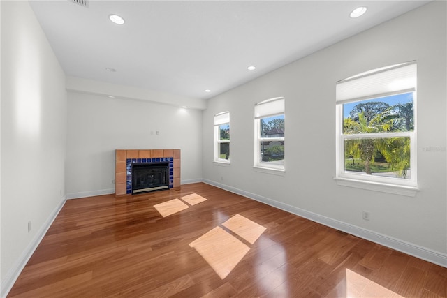 unfurnished living room with hardwood / wood-style floors and a tiled fireplace