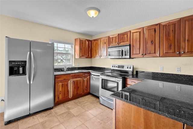 kitchen with dark stone countertops, sink, and stainless steel appliances