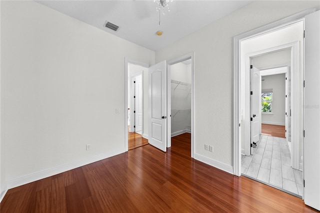 unfurnished bedroom with a spacious closet, wood-type flooring, and a closet