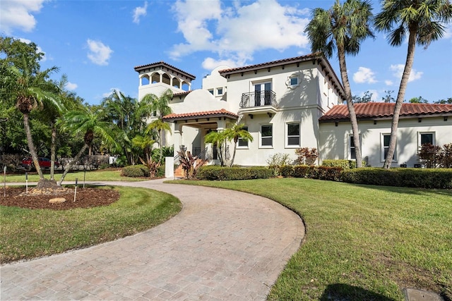 mediterranean / spanish house featuring a balcony and a front lawn