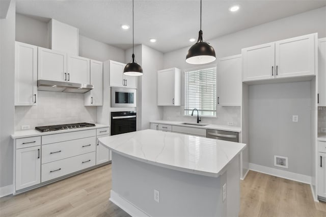 kitchen with sink, decorative light fixtures, a kitchen island, white cabinetry, and stainless steel appliances