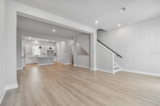 unfurnished living room with sink and light hardwood / wood-style floors