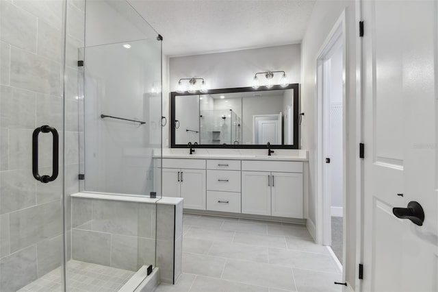 bathroom with tile patterned floors, vanity, an enclosed shower, and a textured ceiling