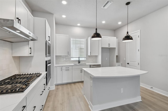 kitchen with stainless steel appliances, sink, pendant lighting, light hardwood / wood-style floors, and white cabinetry