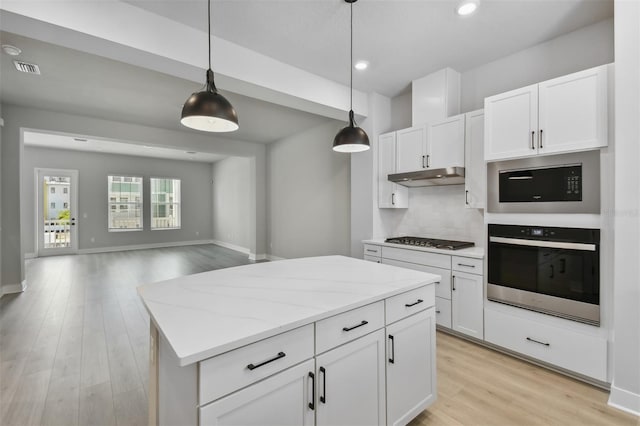 kitchen featuring appliances with stainless steel finishes, decorative light fixtures, decorative backsplash, white cabinets, and light wood-type flooring