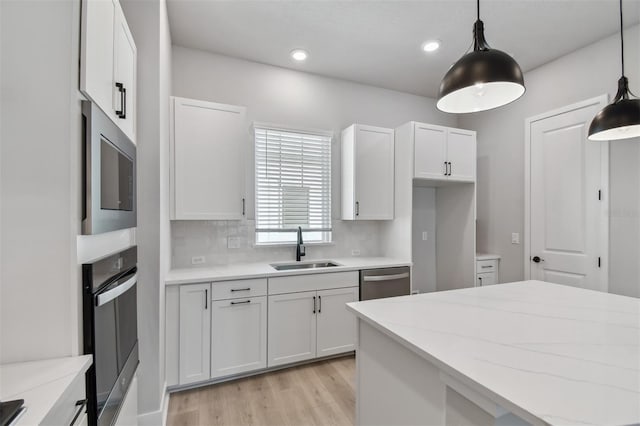 kitchen featuring pendant lighting, sink, tasteful backsplash, white cabinetry, and stainless steel appliances