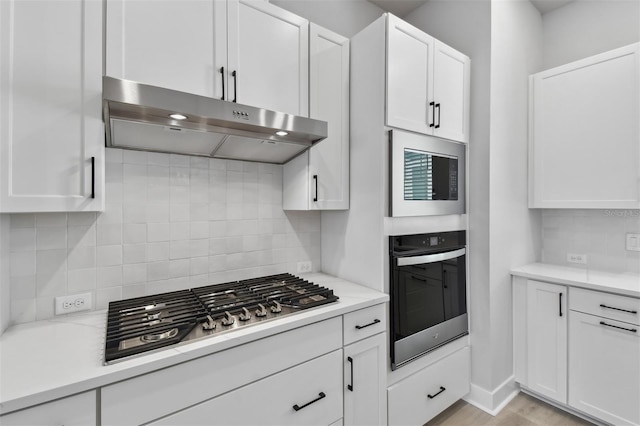 kitchen featuring white cabinets, backsplash, light wood-type flooring, and stainless steel appliances