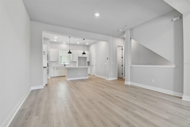 unfurnished living room with light hardwood / wood-style flooring and sink