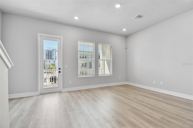 spare room with light hardwood / wood-style flooring and a textured ceiling