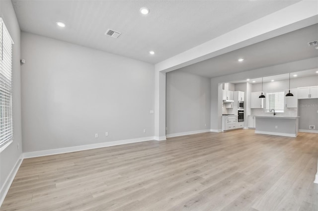 unfurnished living room featuring light hardwood / wood-style flooring and sink