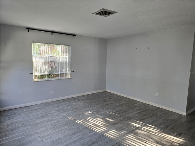 empty room featuring a textured ceiling and dark hardwood / wood-style flooring